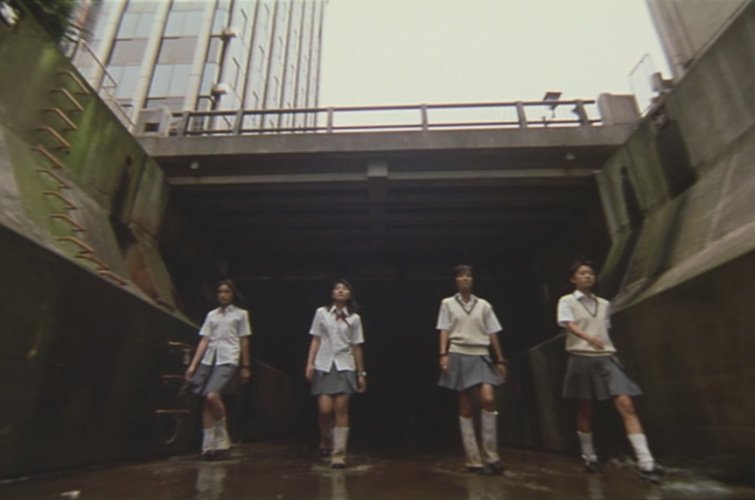 A still from the movie showing the four main characters walking down the Shibuya river in Tokyo.